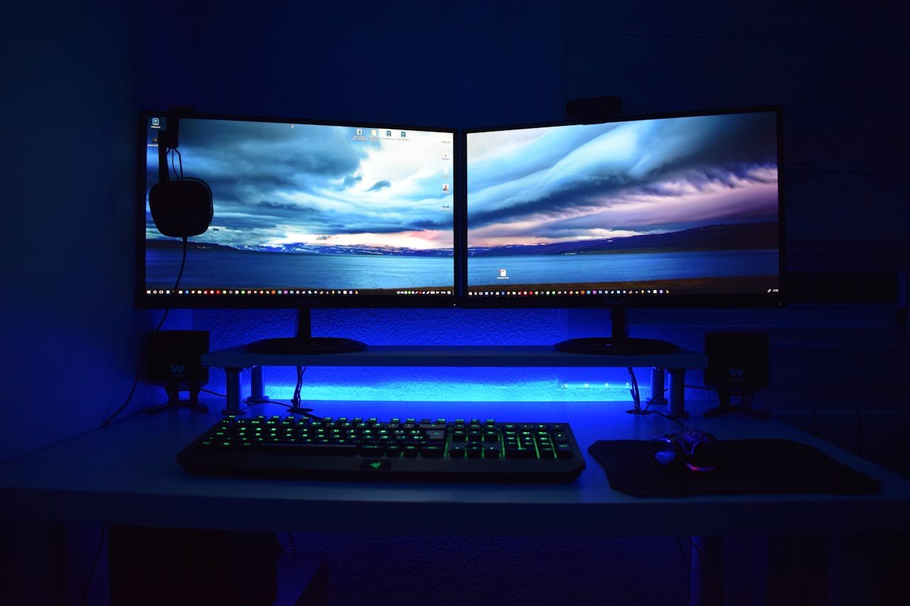 about-01 Dual monitors with blue lighting on a gaming desk setup.